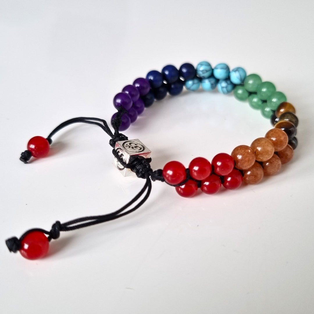 Handmade bracelet with 7 chakra crystal gemstones, featuring amethyst, lapis lazuli, blue aquamarine, green aventurine, tiger’s eye, Orange stone, and red agate."